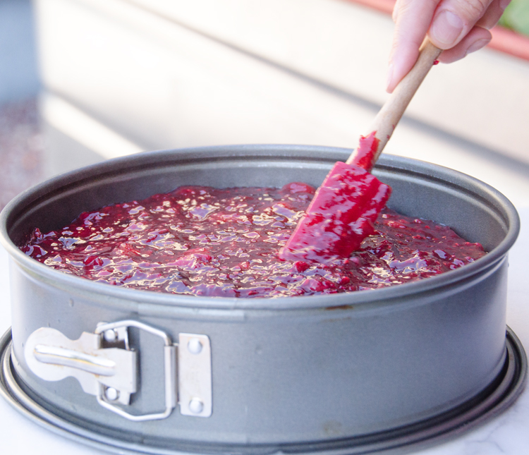 Pouring rote Grütze onto cheesecake